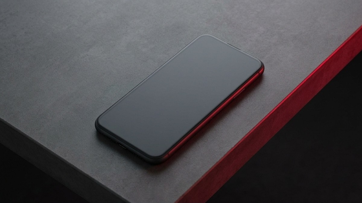 Conceptual AI illustration: A charcoal smartphone on a gray desk with crimson edge light.