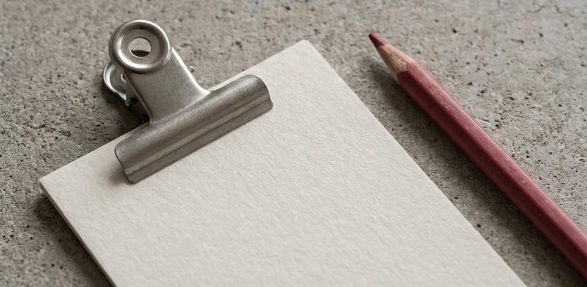 Conceptual AI illustration: A blank inspection card beneath a steel clip beside a crimson pencil.