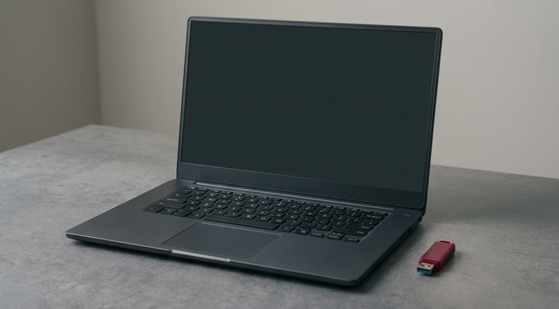 Conceptual AI illustration: An unbranded laptop and crimson installation drive on a gray surface.