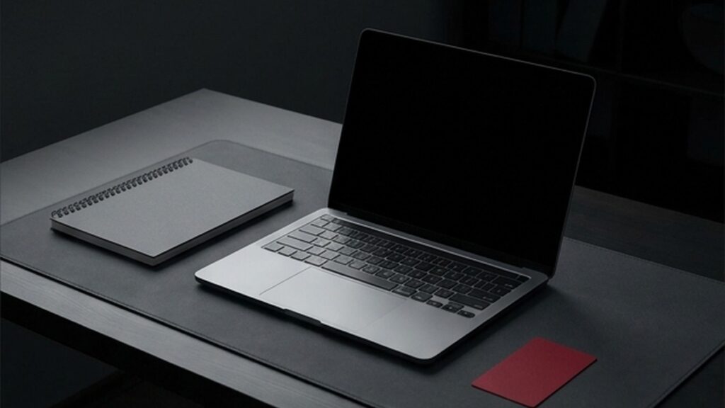 Conceptual AI illustration: A laptop, notebook, and separate crimson card on a clean desk.