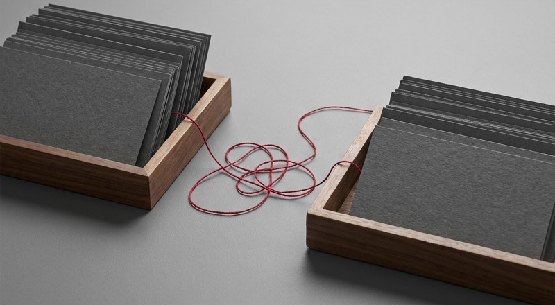 Conceptual AI illustration: Two trays of blank charcoal cards linked by red thread.